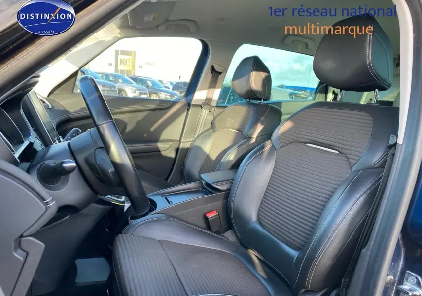 Vue intérieure côté conducteur du Renault Grand Scenic IV bleu, sièges avant en similicuir noir avec surpiqûres blanches.