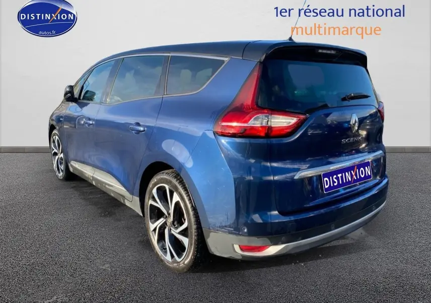 Vue 3/4 arrière droite d'un Renault Grand Scénic IV bleu avec jantes alliage 20 pouces et vitres surteintées.