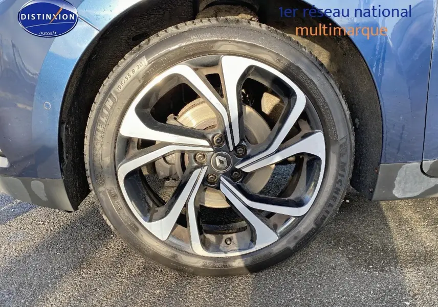 Gros plan sur la roue avant gauche du Renault Grand Scenic IV bleu, avec jante alliage 20 pouces et logo Renault central.