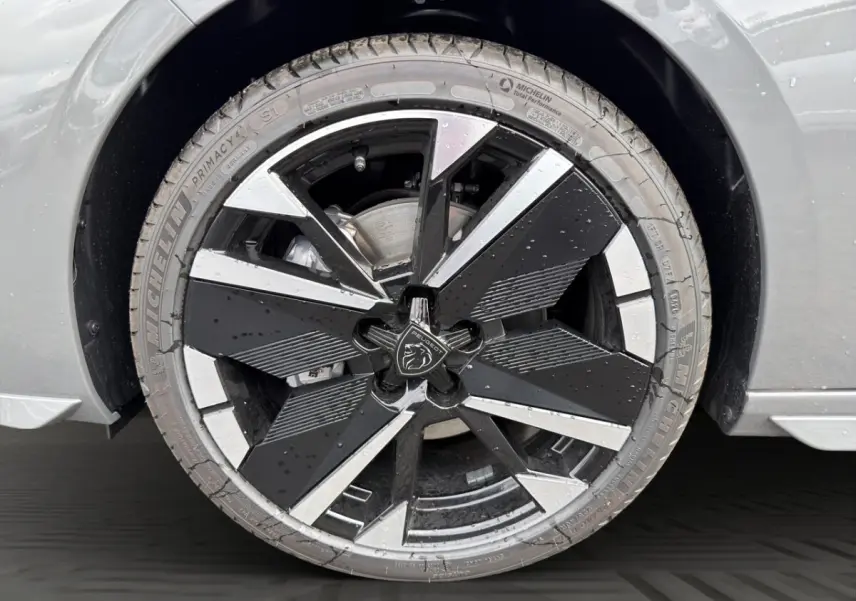 Gros plan sur la roue avant droite gris clair de la Peugeot 308 avec jante noire et argentée au design géométrique.