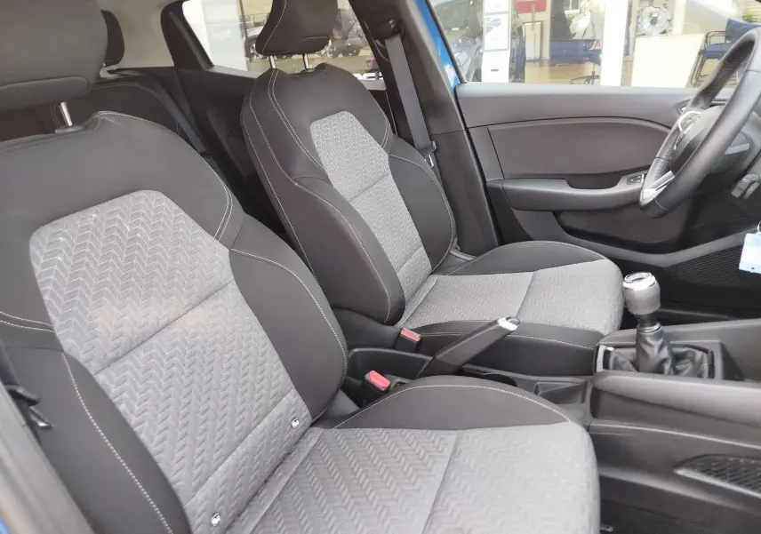 Vue intérieure côté droit de la Renault Clio 2022, montrant les sièges gris à motifs et la boîte manuelle.