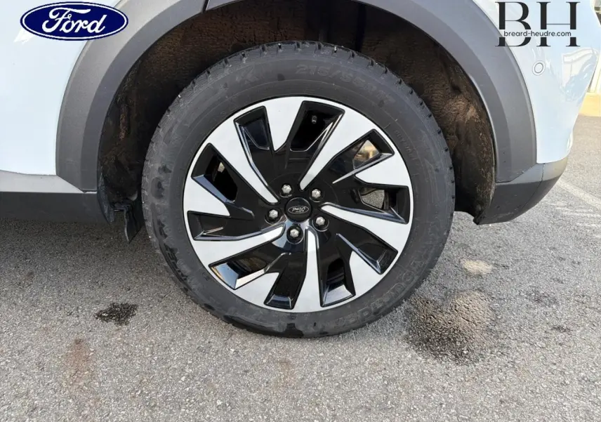 Gros plan sur la roue avant droite du Ford Puma blanc Glacier, mettant en valeur la jante bicolore noire et argent.