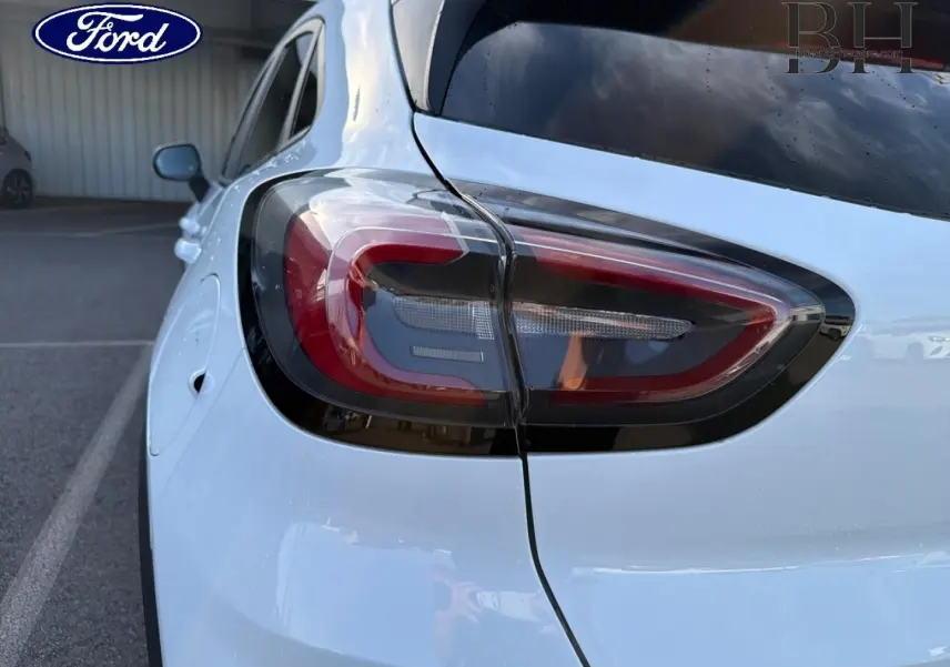 Gros plan sur le feu arrière gauche d’un Ford Puma blanc Glacier, avec hayon électrique visible en partie.