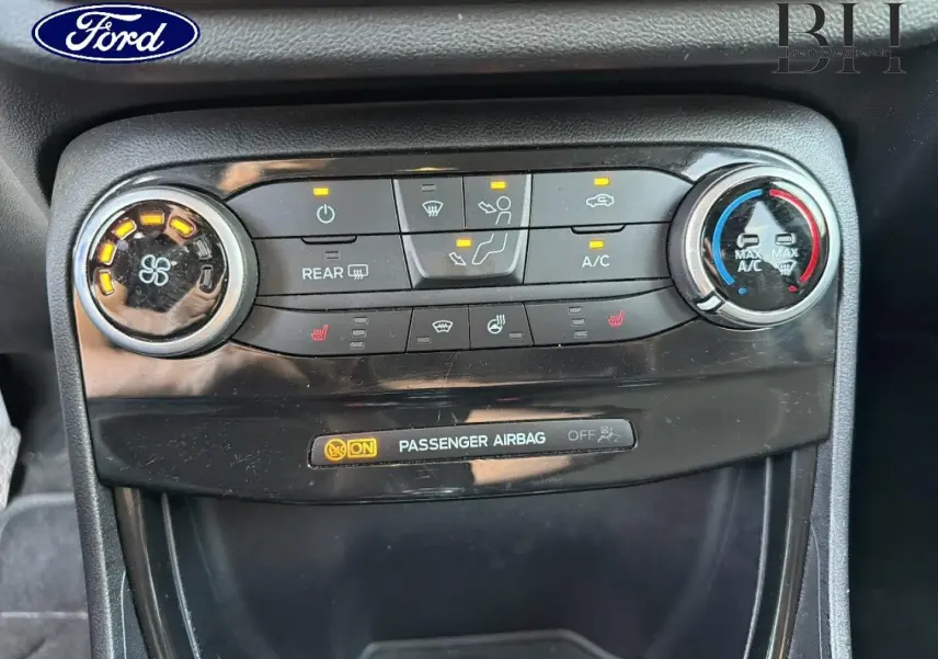 Vue rapprochée du tableau de bord central noir du Ford Puma 2023, montrant les commandes de climatisation et l'indicateur airbag passager.