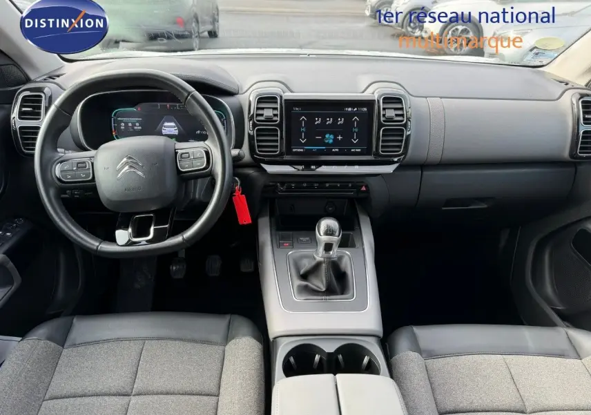 Vue intérieure avant du Citroën C5 Aircross blanc nacré, montrant tableau de bord, volant et console centrale avec boîte manuelle.