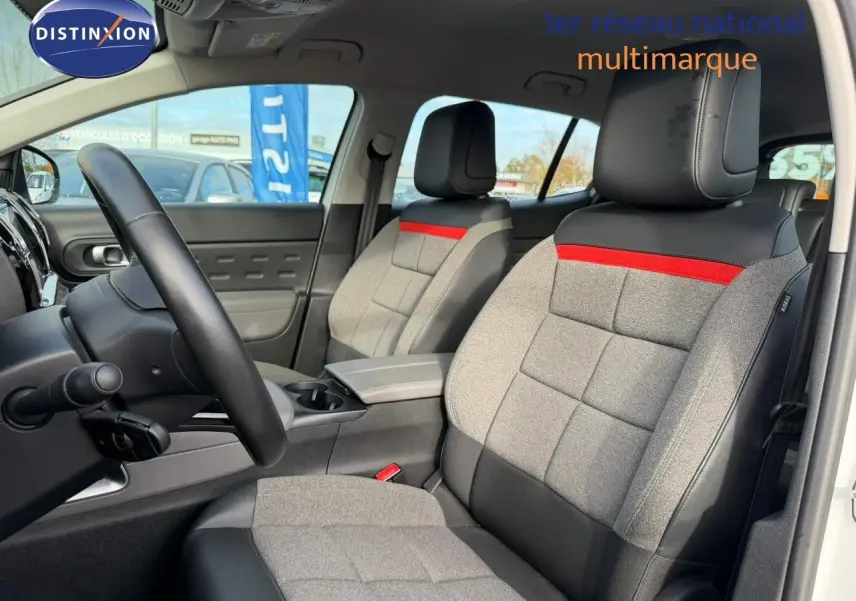 Vue intérieure des sièges avant en tissu gris et cuir noir avec bande rouge, dans un Citroën C5 Aircross blanc nacré.