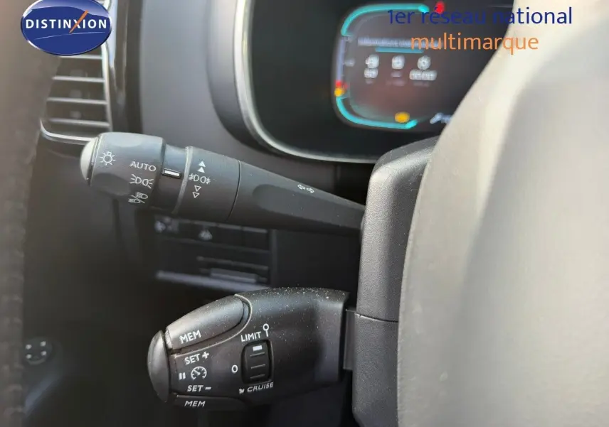 Gros plan sur les commandes au volant du Citroën C5 Aircross blanc nacré, avec tableau de bord numérique en arrière-plan flou.