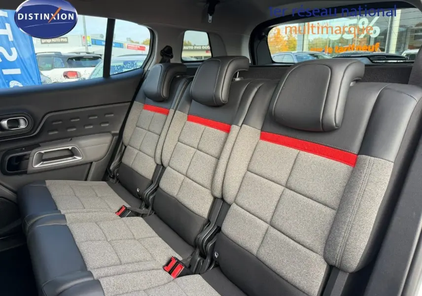Vue intérieure des sièges arrière du Citroën C5 Aircross blanc nacré, avec sellerie grise, noire et bande rouge distinctive.