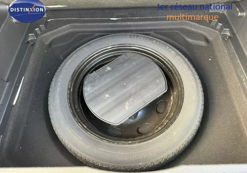 Vue rapprochée de la roue de secours noire dans le coffre d’un Citroën C5 Aircross blanc nacré de 2019.