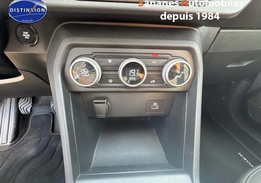Vue rapprochée de la console centrale noire du Dacia Jogger 2023, avec commandes de climatisation et prise USB visible.