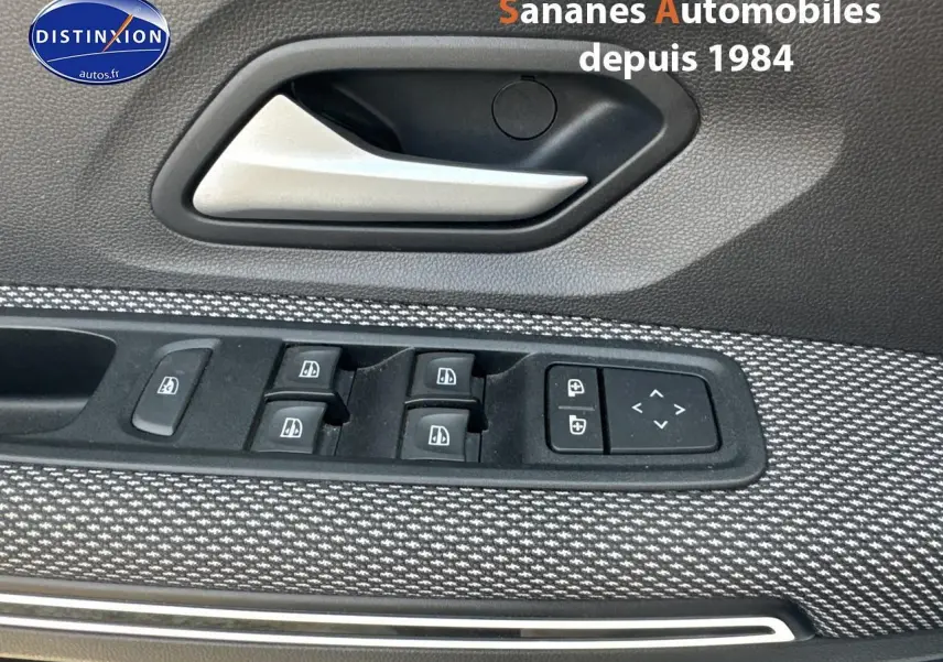 Gros plan sur la commande des vitres électriques et la poignée intérieure côté conducteur du Dacia Jogger blanc.