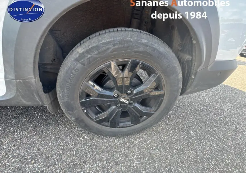 Gros plan sur la roue arrière gauche avec jante aluminium noire du Dacia Jogger blanc Glacier 2023 version Extrême+