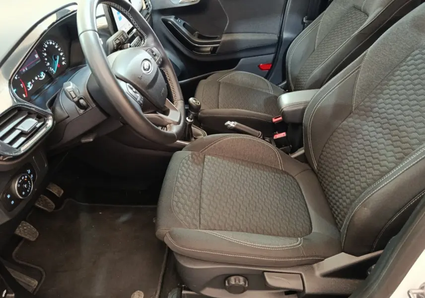 Intérieur avant droit du Ford Puma blanc 2022, sièges tissu gris, volant multifonctions et levier de vitesse manuel visibles.