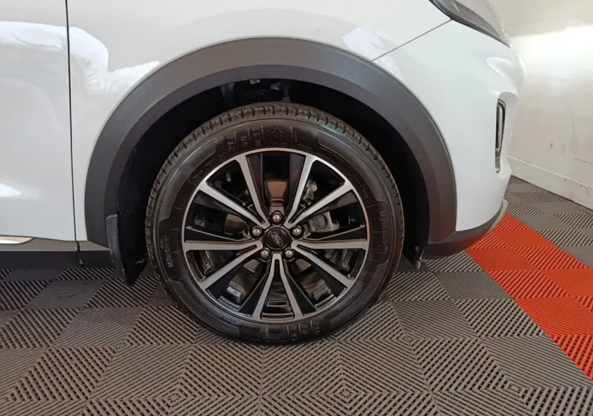 Gros plan sur la roue avant droite noire et argentée du Ford Puma blanc, avec passage de roue en plastique noir.