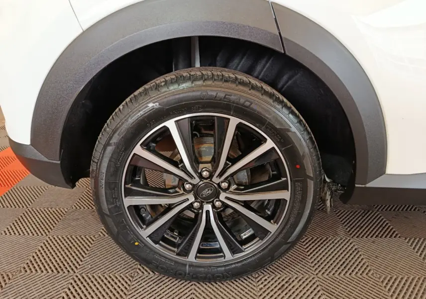 Gros plan sur la roue arrière droite noire et argentée du Ford Puma blanc, avec passage de roue en plastique noir.