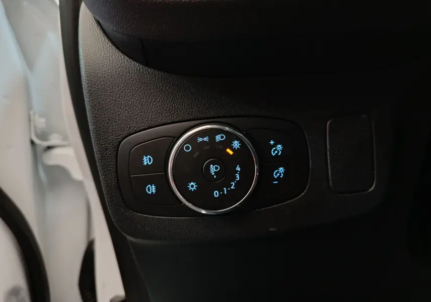 Gros plan sur le bouton de réglage des phares à LED du Ford Puma blanc, côté gauche intérieur conducteur.
