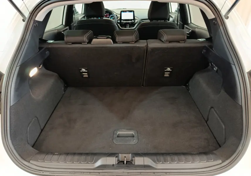 Coffre ouvert vu de l'arrière d'un Ford Puma blanc, montrant l'espace de chargement avec banquette arrière noire.