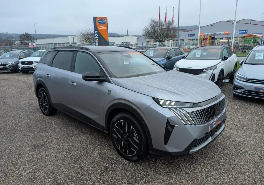 Peugeot 5008 gris métallisé vue 3/4 avant droit, avec jantes alliage noires et feux LED distinctifs.