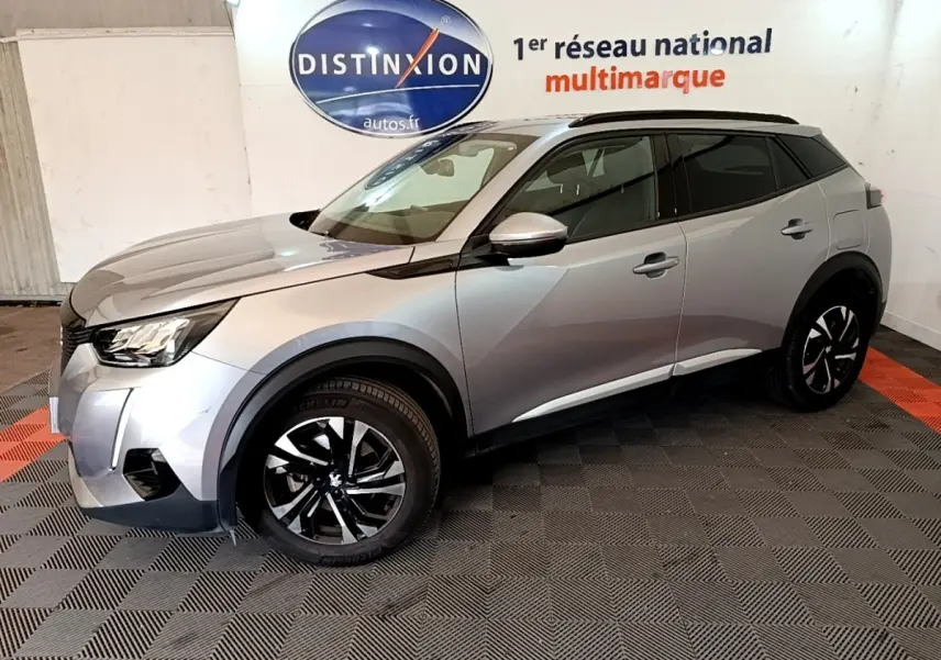 Peugeot 2008 gris clair vue de profil droit en intérieur, avec jantes noires et toit noir contrasté.