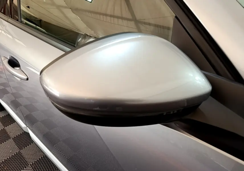 Gros plan sur le rétroviseur droit gris clair du Peugeot 2008, avec la portière et poignée visibles en arrière-plan.