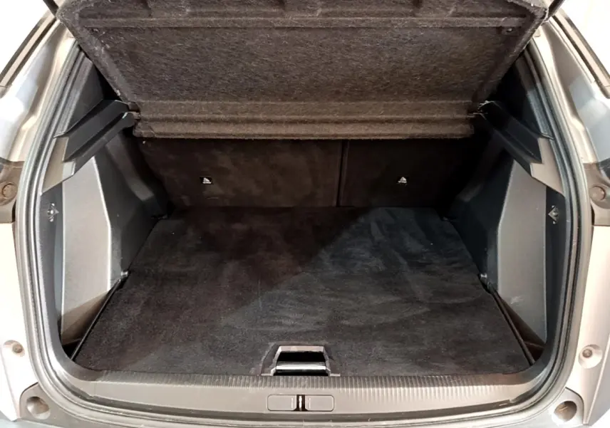 Coffre ouvert vu de l'arrière d'un Peugeot 2008 gris clair, montrant le plancher plat et la banquette rabattable.