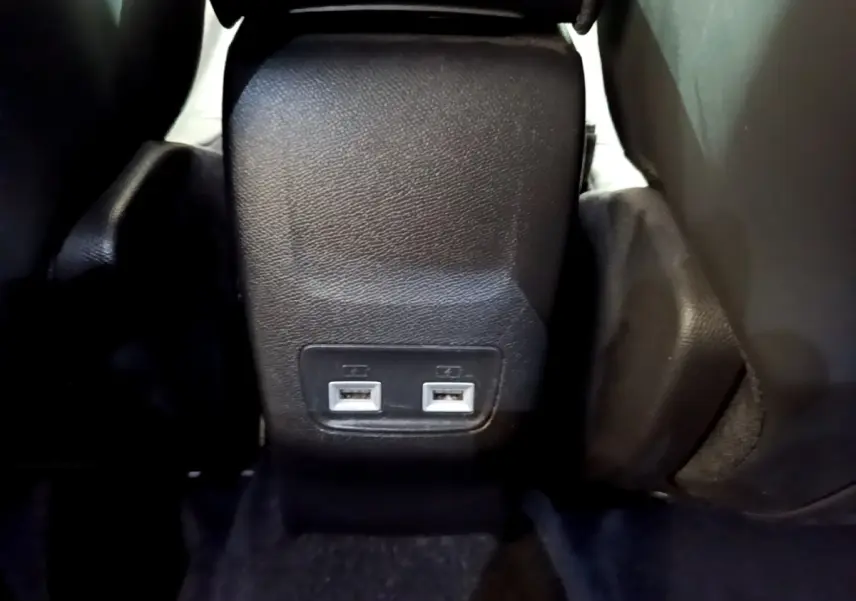 Prise double USB arrière sur console centrale noire du Peugeot 2008 gris clair, vue rapprochée du plancher arrière.