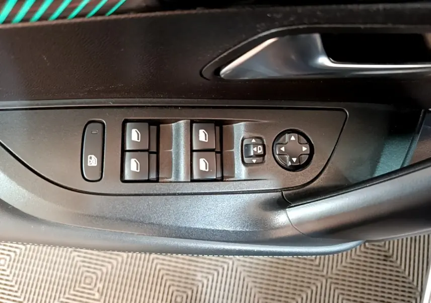 Gros plan sur les commandes de lève-vitres et réglage des rétroviseurs sur la porte côté conducteur du Peugeot 2008 gris clair.