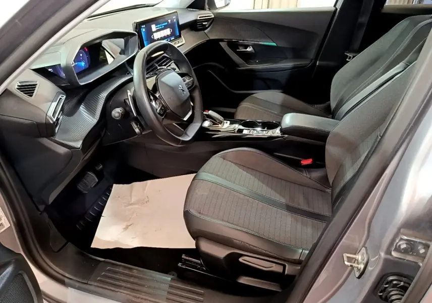 Intérieur côté conducteur du Peugeot 2008 gris clair 2021, avec tableau de bord numérique et volant cuir multifonctions.