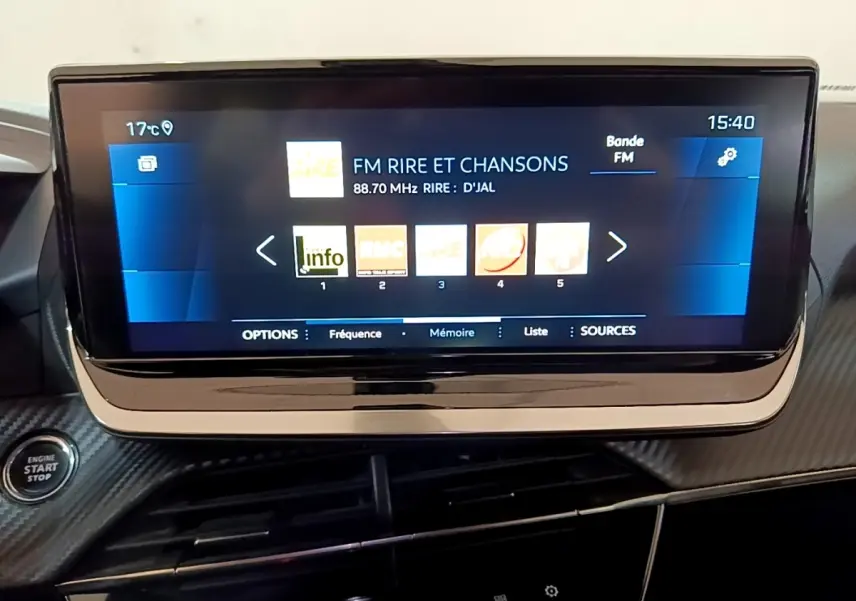 Écran tactile central affichant la radio FM dans l’habitacle du Peugeot 2008 gris clair, vue rapprochée du tableau de bord.