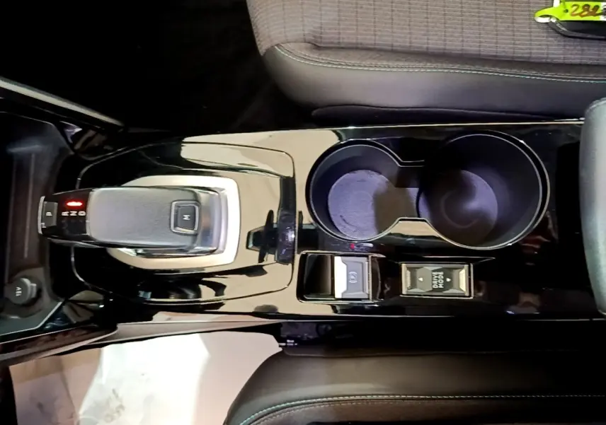Vue plongeante sur la console centrale noire brillante du Peugeot 2008 avec levier de vitesse automatique et porte-gobelets.