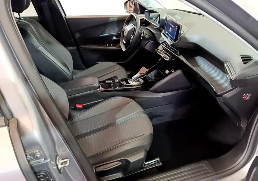 Vue intérieure côté conducteur du Peugeot 2008 gris clair, mettant en valeur les sièges, le volant cuir et l'écran tactile central.
