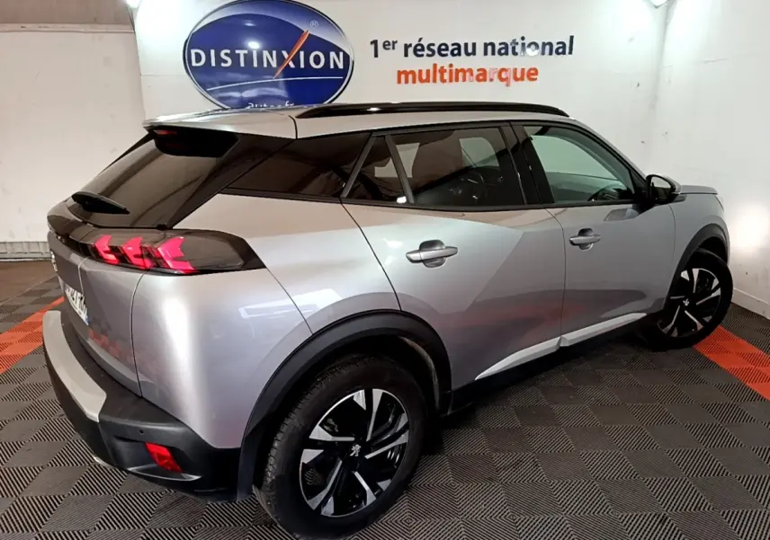 Peugeot 2008 gris clair vue 3/4 arrière droit, avec toit noir et feux arrière à effet griffes rouges.