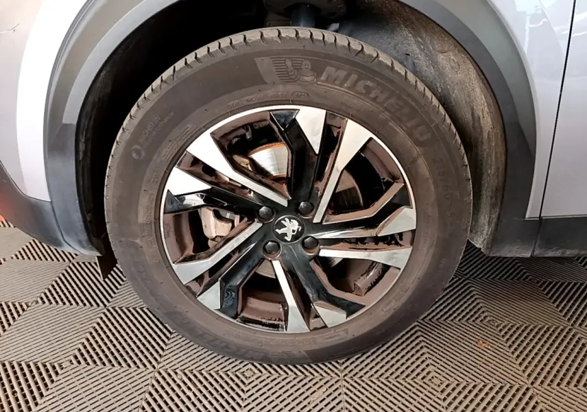 Gros plan sur la roue avant gauche gris clair du Peugeot 2008 avec jante alliage noire et argentée.