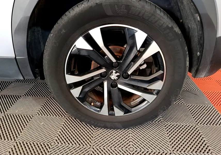 Gros plan sur la roue avant gauche avec jante alliage bicolore noir et argent du Peugeot 2008 gris clair.