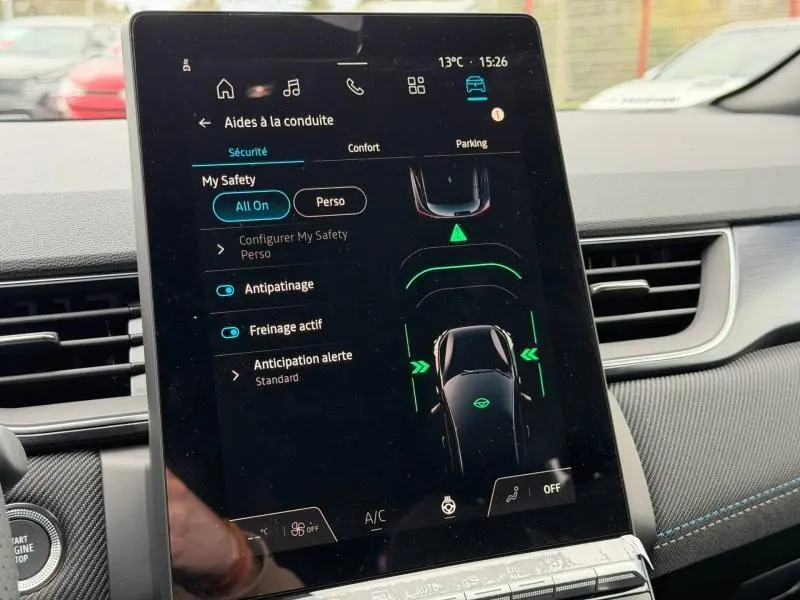 Écran tactile central du Renault Captur 2026 affichant les aides à la conduite, intérieur avec surpiqûres bleues visibles.