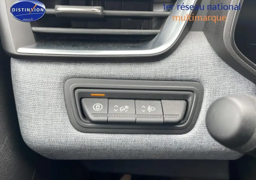 Gros plan sur les commandes d'éclairage et verrouillage, tissu gris à motif 3D dans une Renault Clio V blanche.