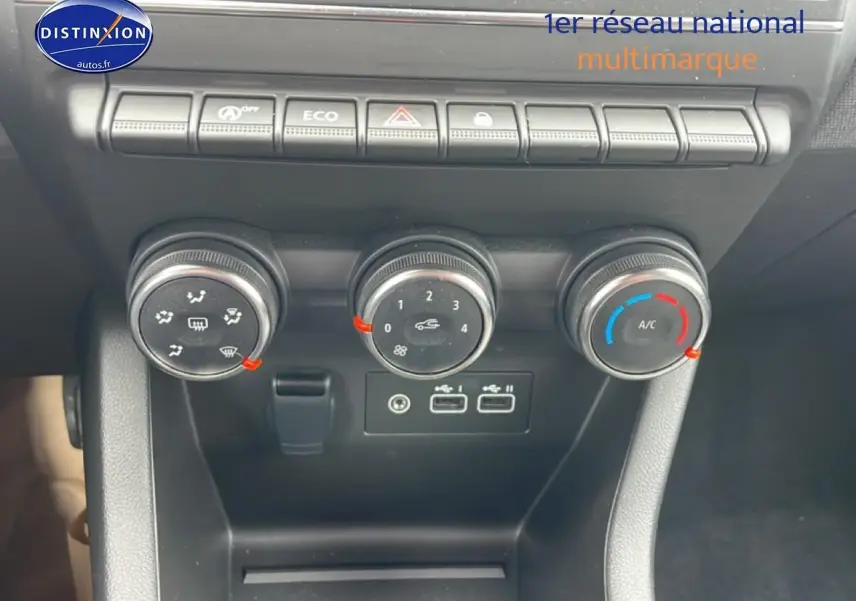 Gros plan sur la console centrale de la Renault Clio V blanche, montrant les commandes de climatisation et ports USB.