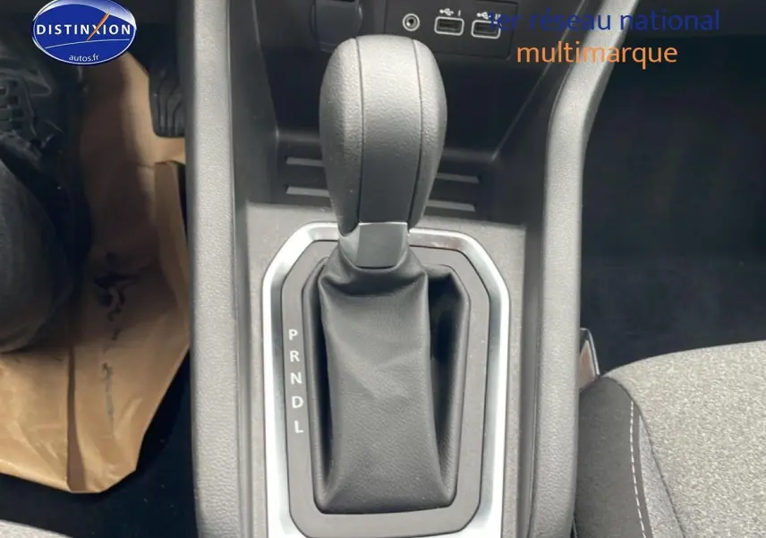 Gros plan sur la commande de boîte automatique noire au centre de la console intérieure d'une Renault Clio V blanche.