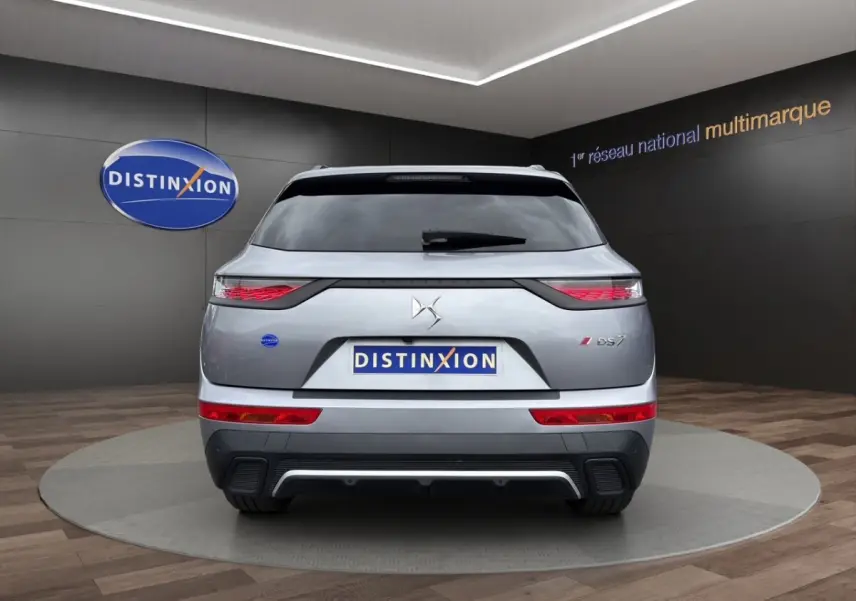 Vue arrière d'un DS7 Crossback gris clair avec feux LED et logo DS bien visibles sur fond intérieur showroom.