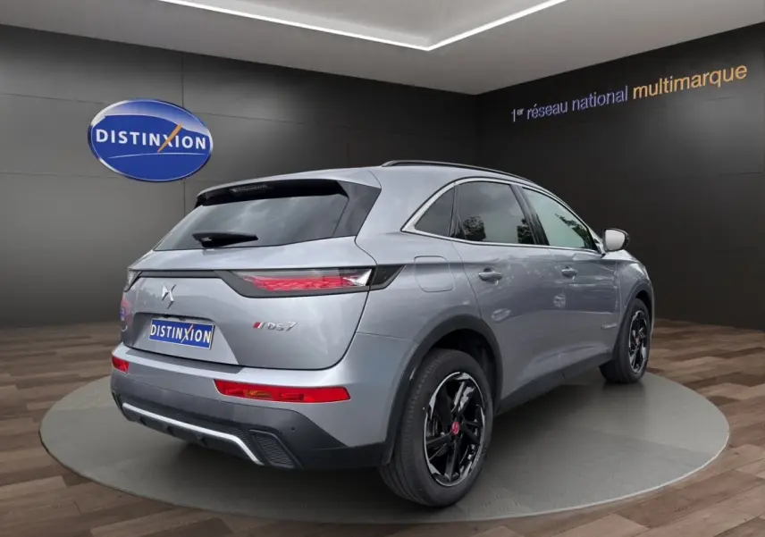 Vue 3/4 arrière droite d’un DS7 Crossback gris clair avec jantes noires et feux arrière LED distinctifs.