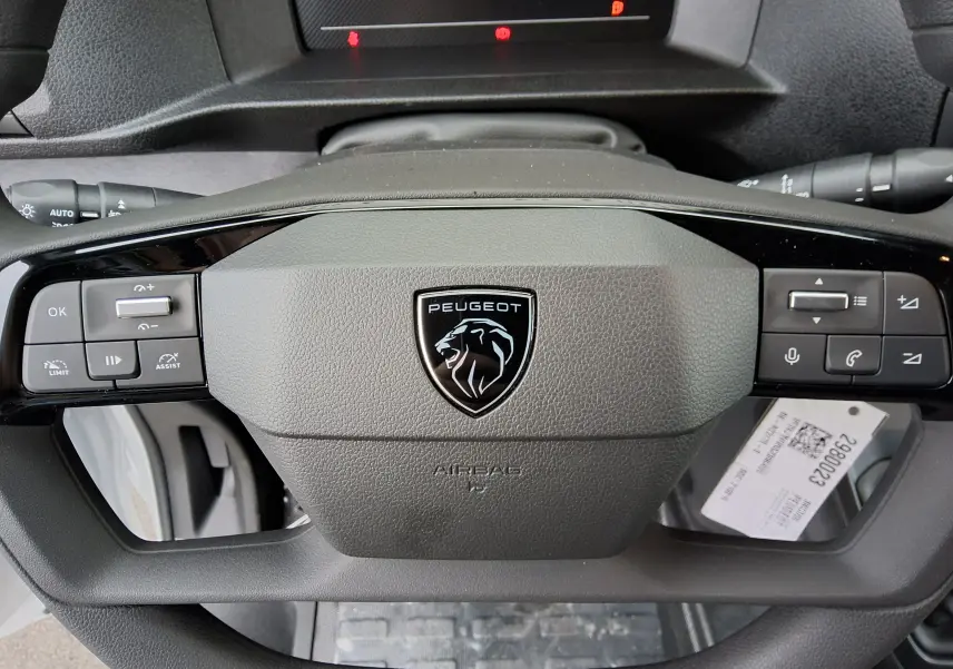 Vue rapprochée du volant gris du Peugeot Expert Fourgon 2025, avec logo lion noir et commandes intégrées.
