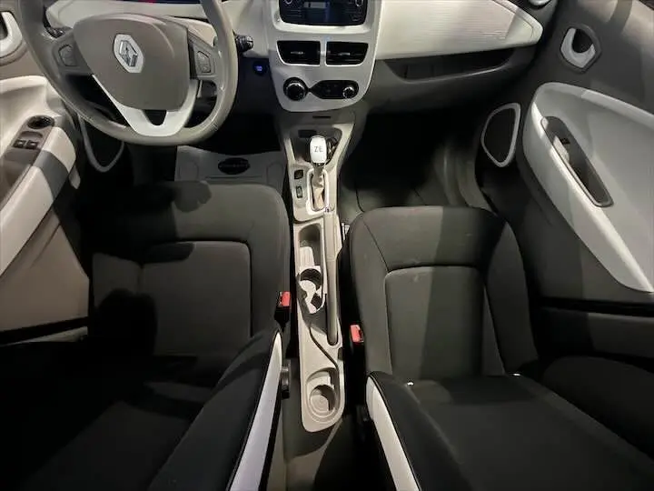 Vue intérieure de la Renault ZOE blanc glacier, montrant les sièges noirs et la console centrale avec levier de vitesse électrique.
