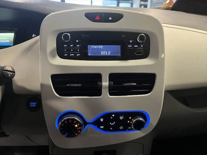 Tableau de bord beige clair de Renault ZOE R90 LIFE 2019 avec radio affichant RTL2 et commandes climatisation rétroéclairées en bleu