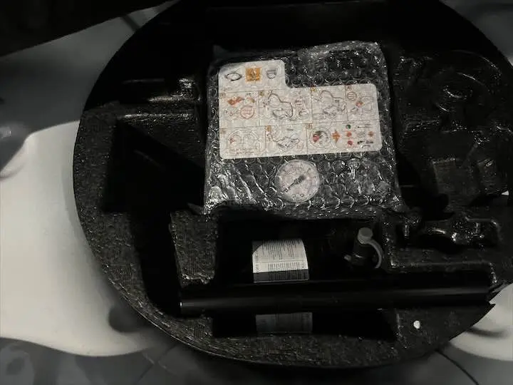 Compresseur et kit de réparation de pneu dans le coffre d'une Renault ZOE blanche vue en gros plan.