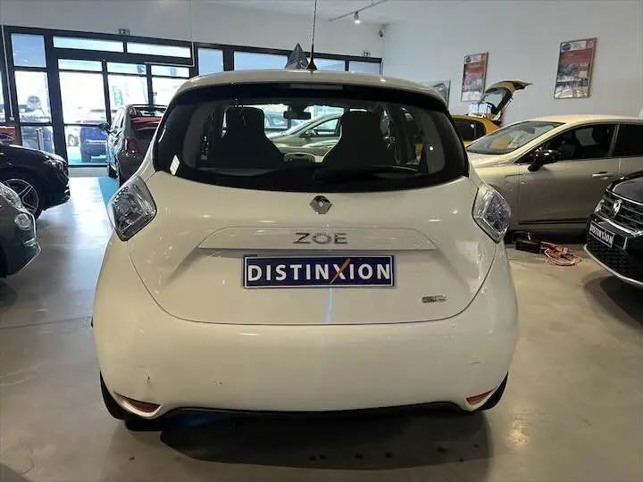 Vue arrière d'une Renault ZOE blanche glacier R90 LIFE 41 KWh avec plaque Distinxion en concession.