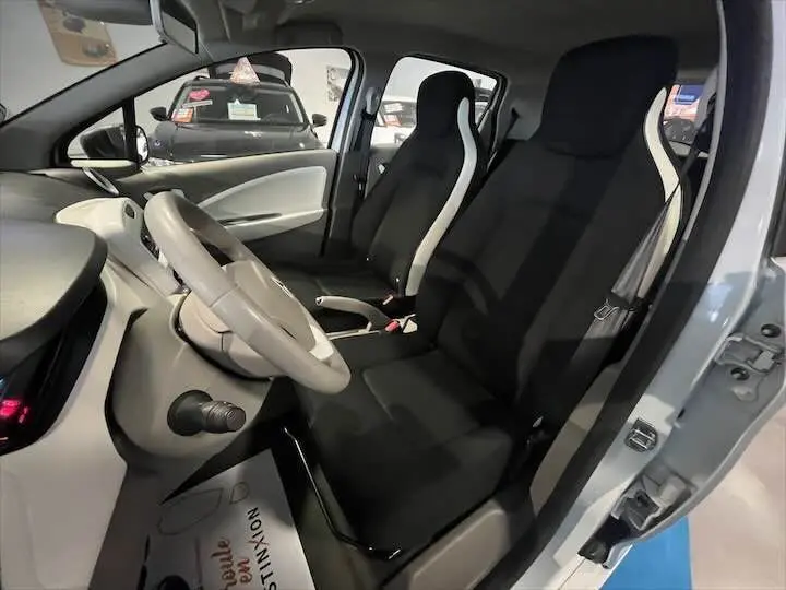 Intérieur de la Renault ZOE R90 Life 2019 en blanc glacier, vue côté gauche sur les sièges avant noirs avec surpiqûres blanches.