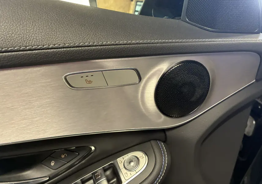 Détail intérieur côté gauche de la porte d'une Mercedes Classe C Break 220D AMG Line 2021, avec bouton siège chauffant et haut-parleur.