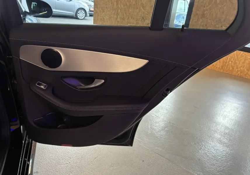 Intérieur de la porte arrière droite d'une Mercedes Classe C Break 220D AMG Line noire, avec habillage cuir et insert aluminium.