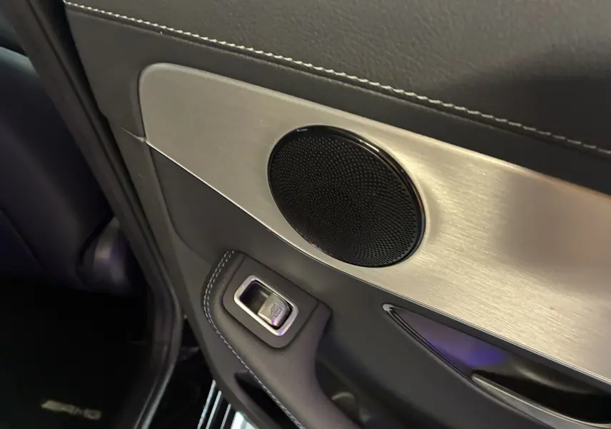 Gros plan sur la garniture intérieure noire et argentée de la porte arrière gauche du Mercedes Classe C Break noir métal AMG Line.