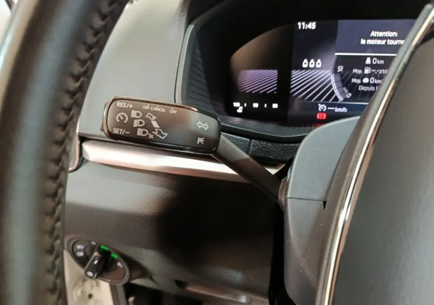 Gros plan sur le commodo gauche et le combiné d'instruments numérique du Skoda Karoq blanc 2024, intérieur noir.